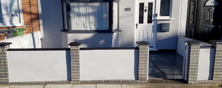 Blue perfurated brick wall with black coping and caps and grey rendering