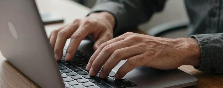 A close-up of a person's hands typing on a laptop in a well-lit North American office, with a cup of coffee nearby, representing productivity and a reliable work environment, charcoal gray tones.