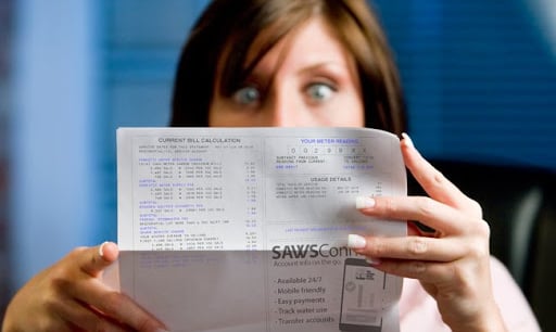 woman looking at a high water bill in shocking manner