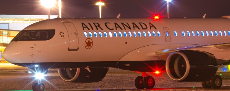 An Air Canada airplane taxis on a snow-covered runway at night with bright terminal lights.VIREMONT 