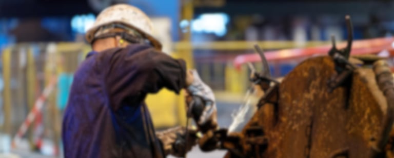 um homem de capacete utilizando uma lixadeira