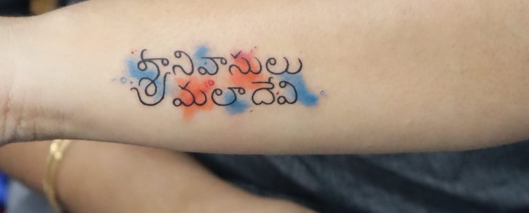 Name tattoo with orange and blue watercolor effect on hand by Dudo’s Hyderabad