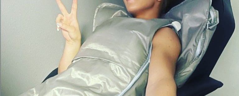 A woman relaxes in a  infrared bodywrap sauna blanket for detox and wellness therapy.