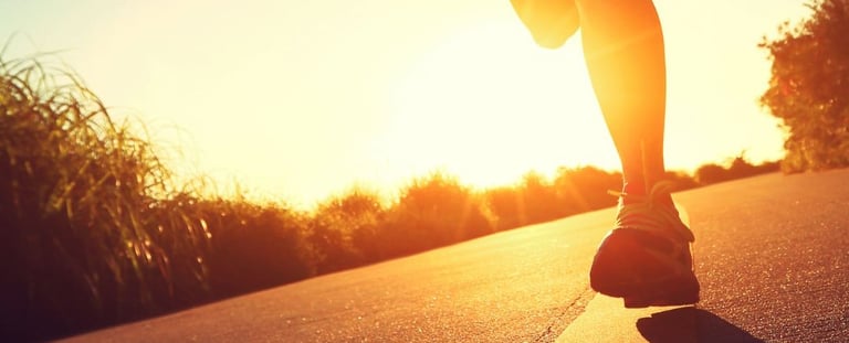a person is running on a road with the sun setting