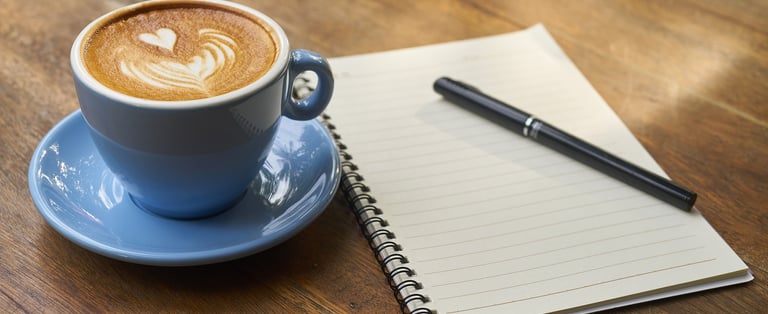 a cup of coffee with a pen and a notebook