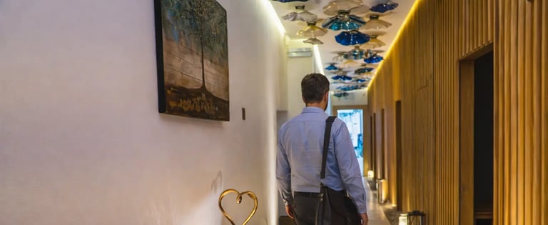 a man walking down a hallway with a table and chairs