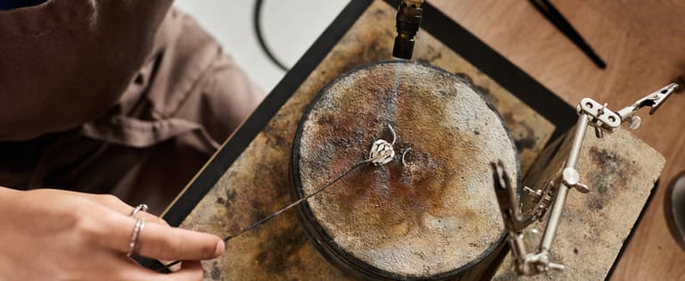 Artesano trabajando la plata a mano, soldando un anillo con soplete en su taller.