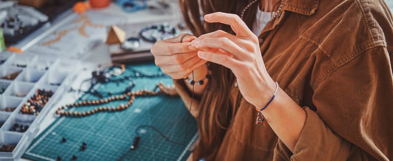Una artesana creando collares y pulseras hechos a mano en un taller creativo.