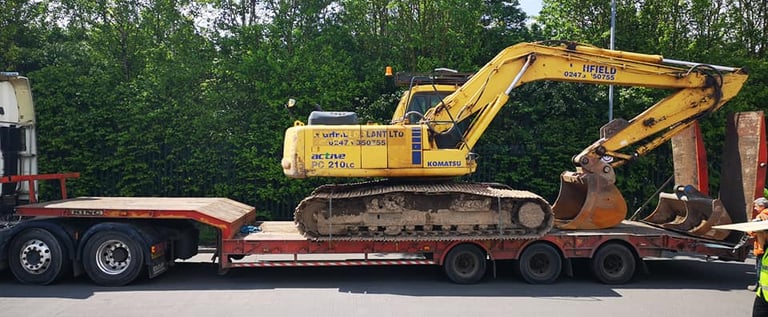 yellow digger loaded on the back of a van in dudley