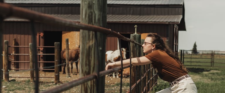 a woman leaning on a fenced in area with a horse