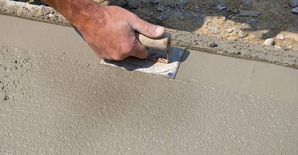 man poring a leveling a concrete slab by hands