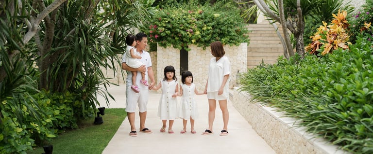 Natalia family walking through tropical garden pathway at The Mulia Nusa Dua Bali during a family photo session