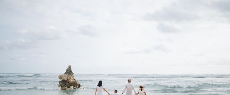 Family standing together facing the ocean at Melasti Beach Bali during a scenic beach photography session