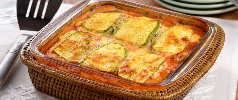 Lasanha low carb de abobrinha com carne moída e queijo gratinado, servida em um prato branco