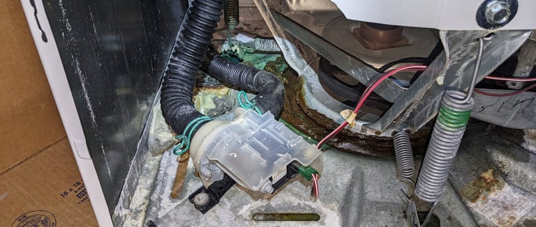 top load washer front panel is removed, drain pump i visible