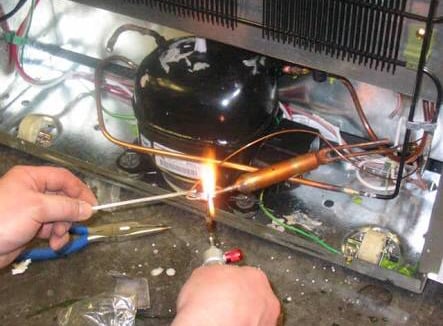 a person soldering a dryer to a compressor