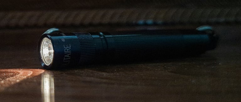  lanterna compacta EDC acesa sobre mesa com itens de everyday carry