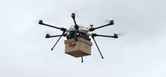 encomenda de delivery sendo carregada por um drone em altitude