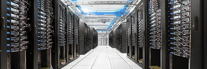 Rows of high-performance server racks in a modern data center facility with blue overhead cabling.