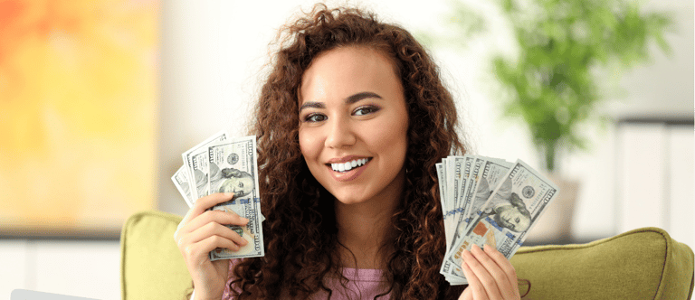 a woman sitting on a couch holding a laptop and holding money