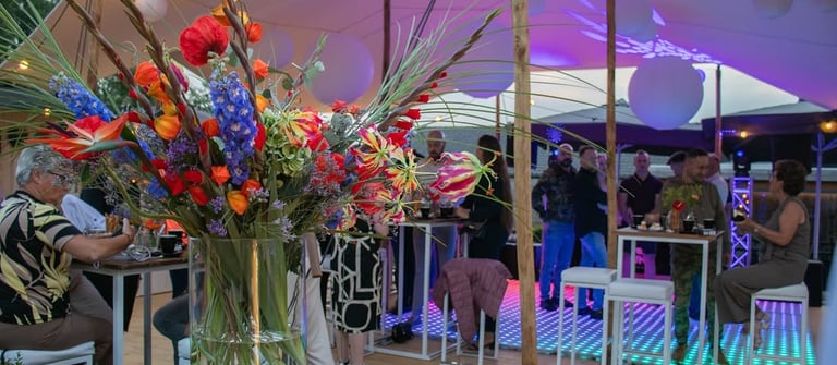 Elegant ingerichte feestzaal met tafels en partyverlichting en muziek.