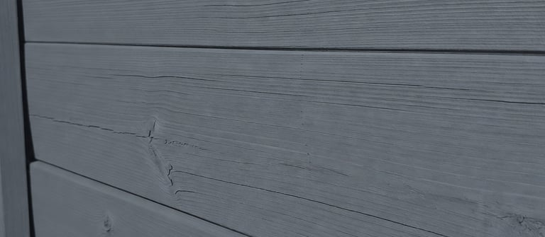 A wood fence with deep grey matte finish created with traditional linseed oil paint