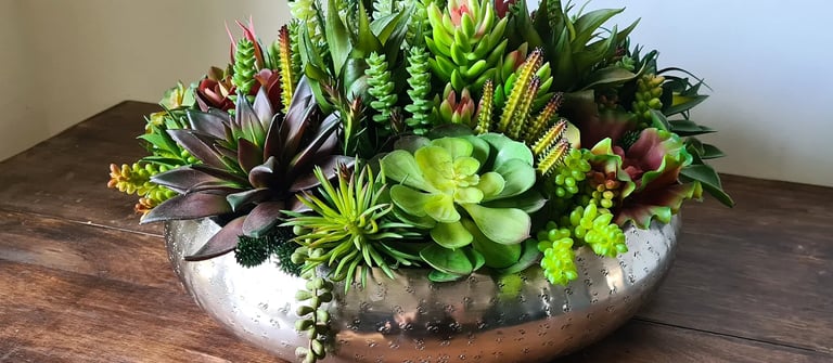 a silver bowl with artificial succulent plants in it