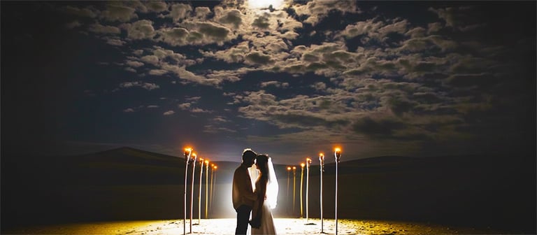 a couple kissing in front of a full moon