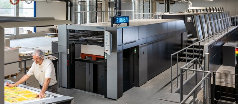 Professional technician operating a high-speed industrial offset printing press in a modern manufacturing facility.