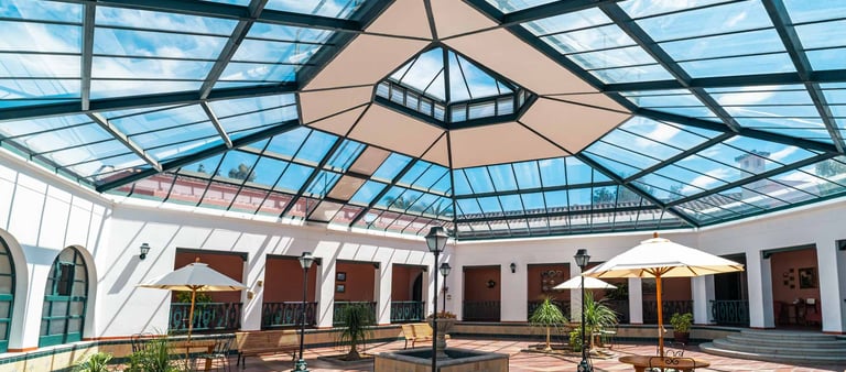 Plaza interna con tragaluz y grandes ventanales zona de descanso con sombrillas y sillas inmueble en Quito Ecuador