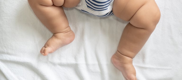jambes d'un bébé en body