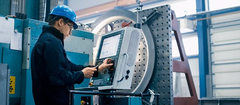 a man in a hard hat and hard hat with a laptop on a machine