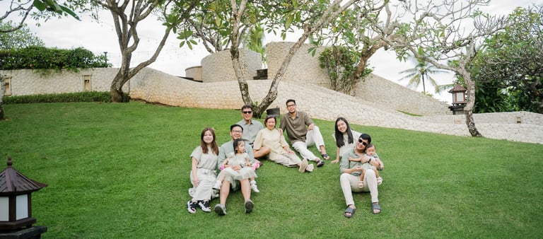 Three generation family gathered on a tropical garden lawn during a family photography session in Bali.