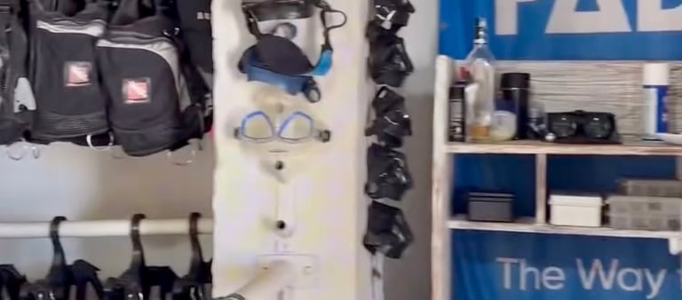 Scuba diving rental shop featuring PADI signs, snorkeling masks, and BCD jackets on racks.