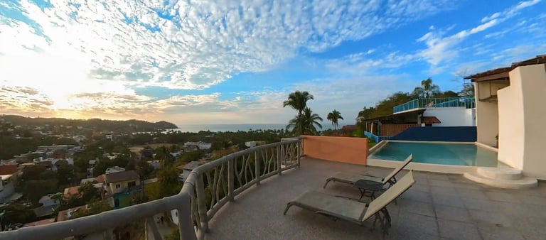 a pool with lounge chairs and a view of the ocean