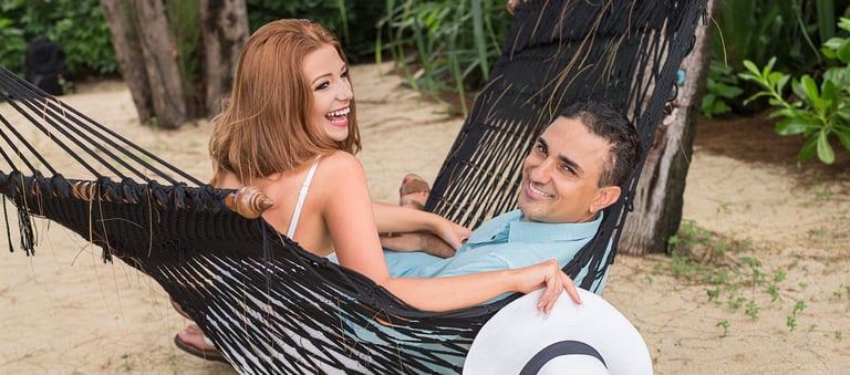 A joyful newlywed couple lounging in a black hammock on a sandy tropical beach in Koh Samui