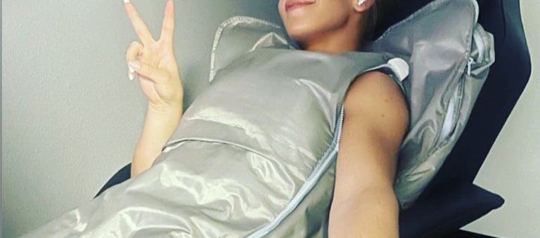 A woman relaxes in a  infrared bodywrap sauna blanket for detox and wellness therapy.