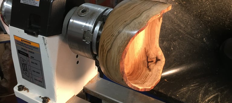 Spalted Cascara Natural Edge Bowl, mounted on lathe, illuminated interior
