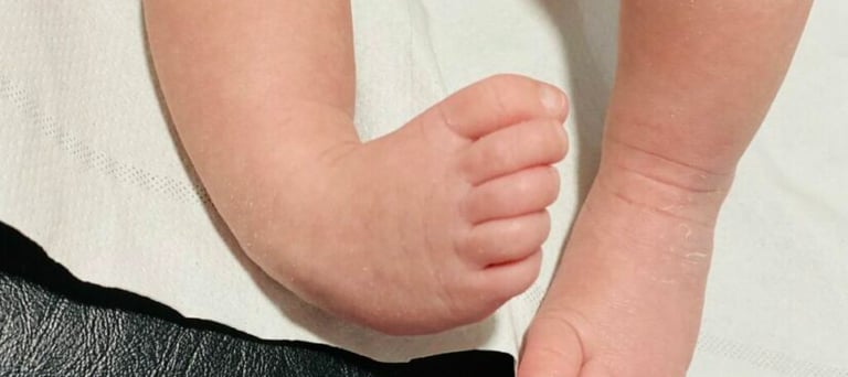 a baby's feet and toes on a white sheet