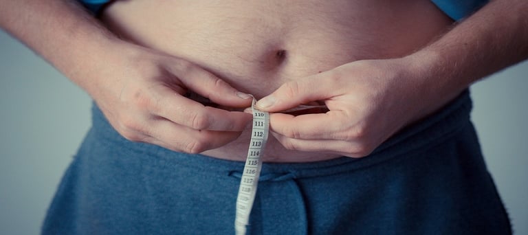 Person holding measuring tape around his stomach