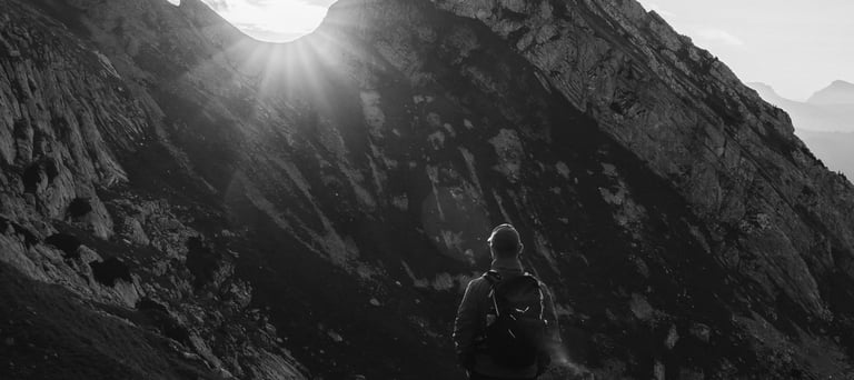 Persona che osserva l’alba tra le montagne, simbolo di introspezione, crescita personale e cammino v