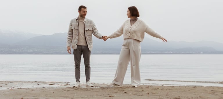 a man and woman holding hands and walking on a beach
