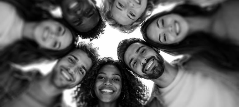 camera looking up to a circle of diverse people in a circle looking down with happy faces