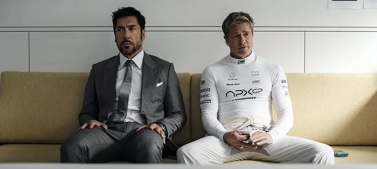 "Brad Pitt in a white racing suit sit side-by-side on a beige couch in a