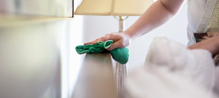 a woman cleaning a bed with a green cloth