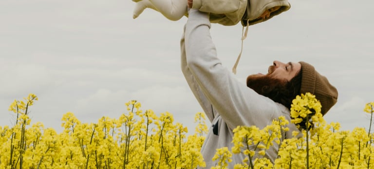 a man holding a baby in a field