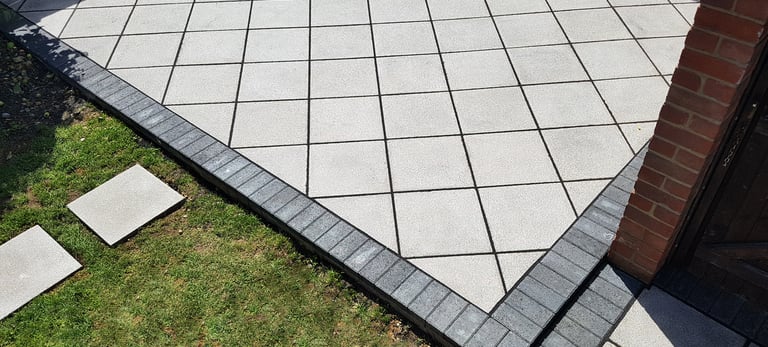 Basic grey patio with black charcoal edging blocks slabs laid in diamond format