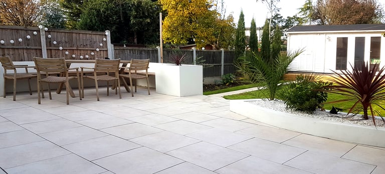 Modern chic raised porcelain patio with white rendered walls and planters