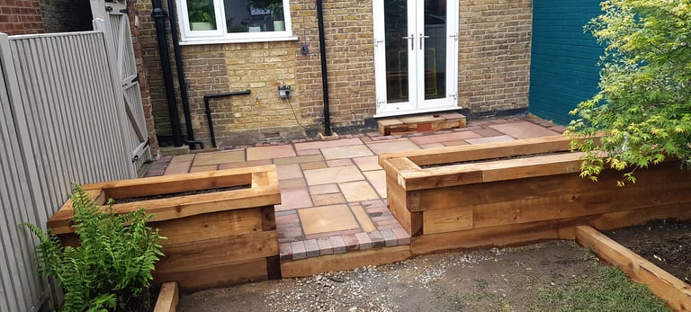 Colourful sandstone patio with raised wooden timber planter seating