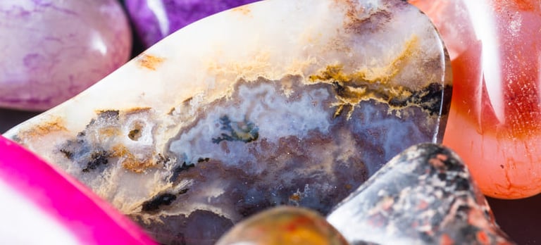 Primer plano de cristales pulidos de sanación y piedras de ágata coloridas en tonos morado, rosa .